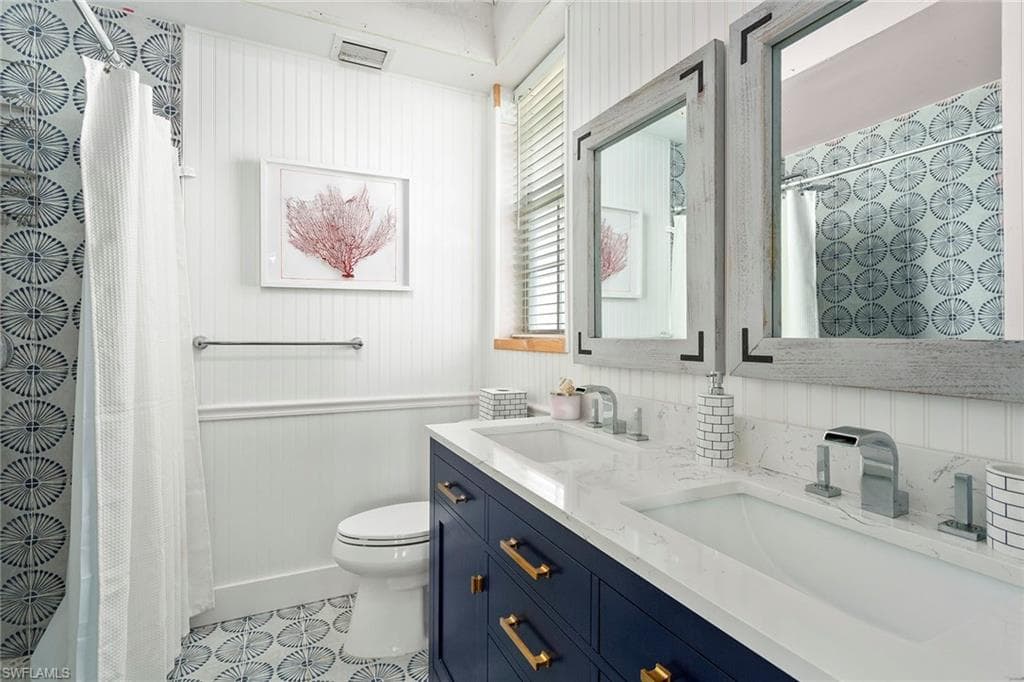 Full bathroom featuring curtained shower, double vanity, and wood walls
