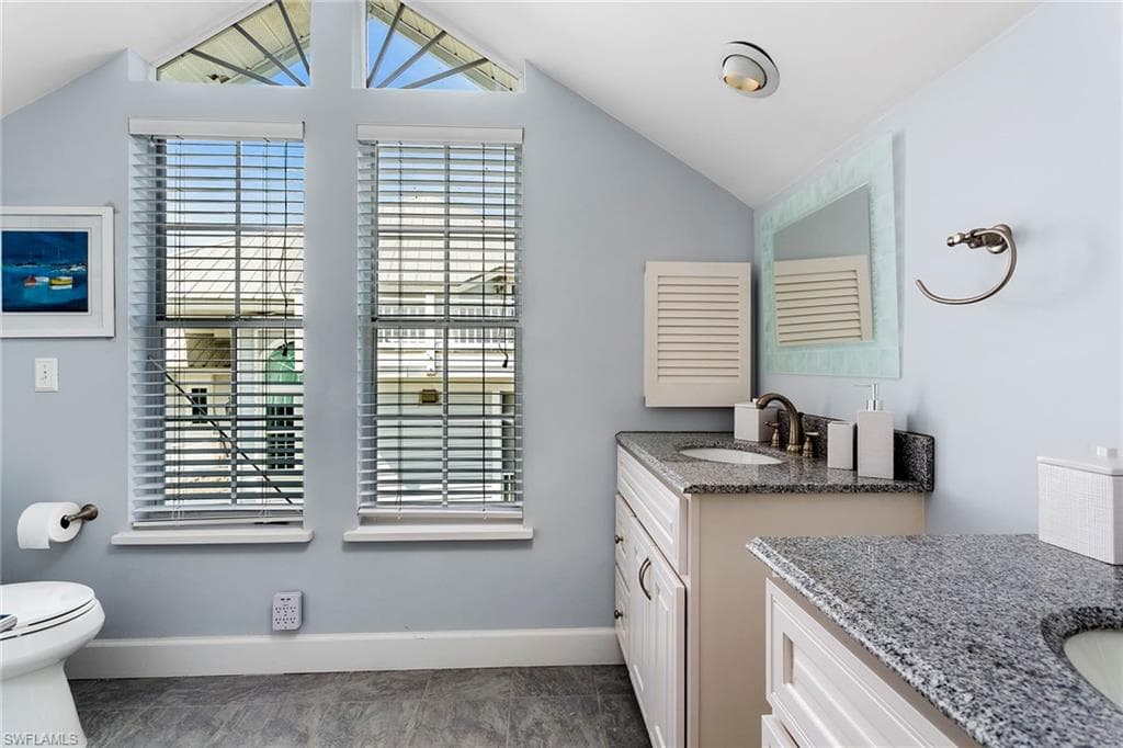 Bathroom featuring two vanities and vaulted ceiling