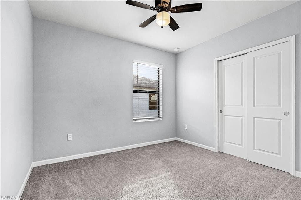 Guest bedroom featuring light colored carpet, a closet, and a ceiling fan