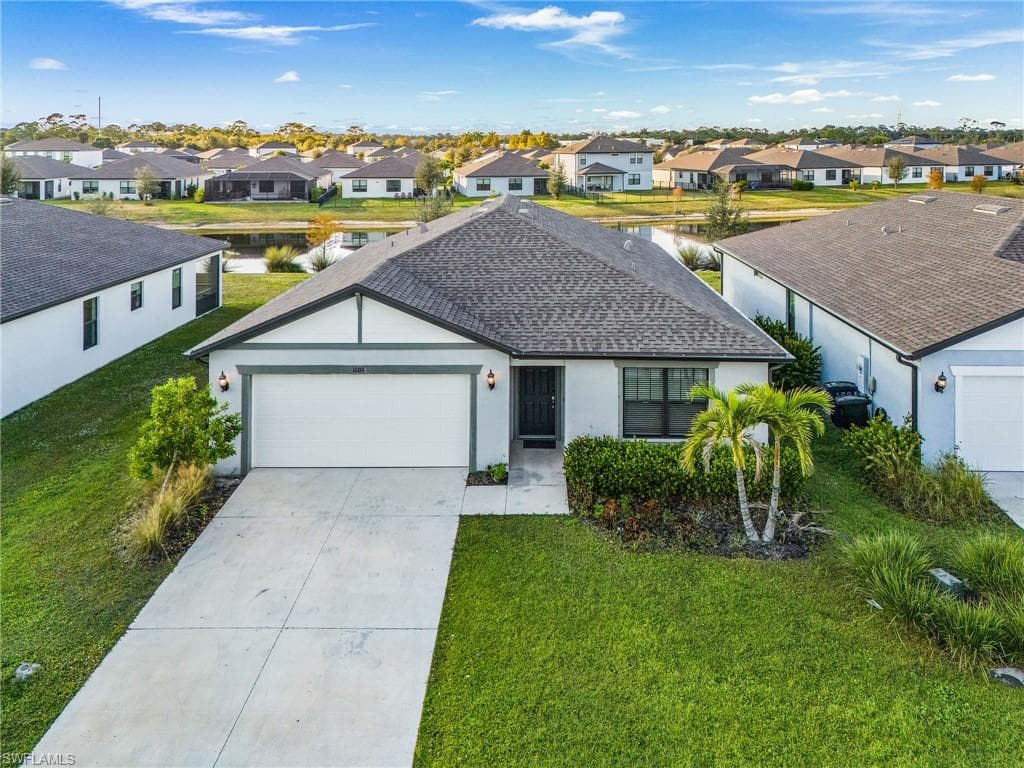 Single story home featuring a front lawn, a residential view, an attached garage, and driveway