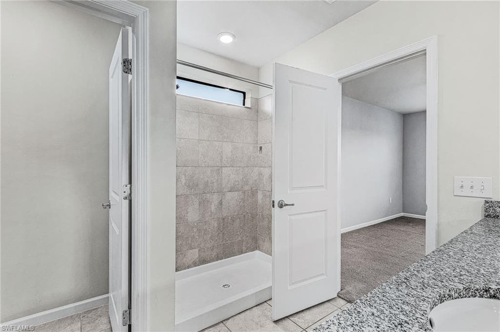 Full bath featuring vanity, a stall shower, and light tile patterned floors