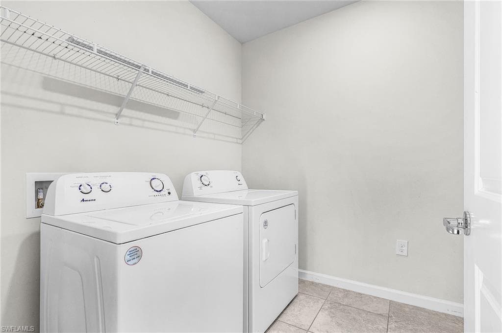 Laundry area with independent washer and dryer and light tile patterned floors