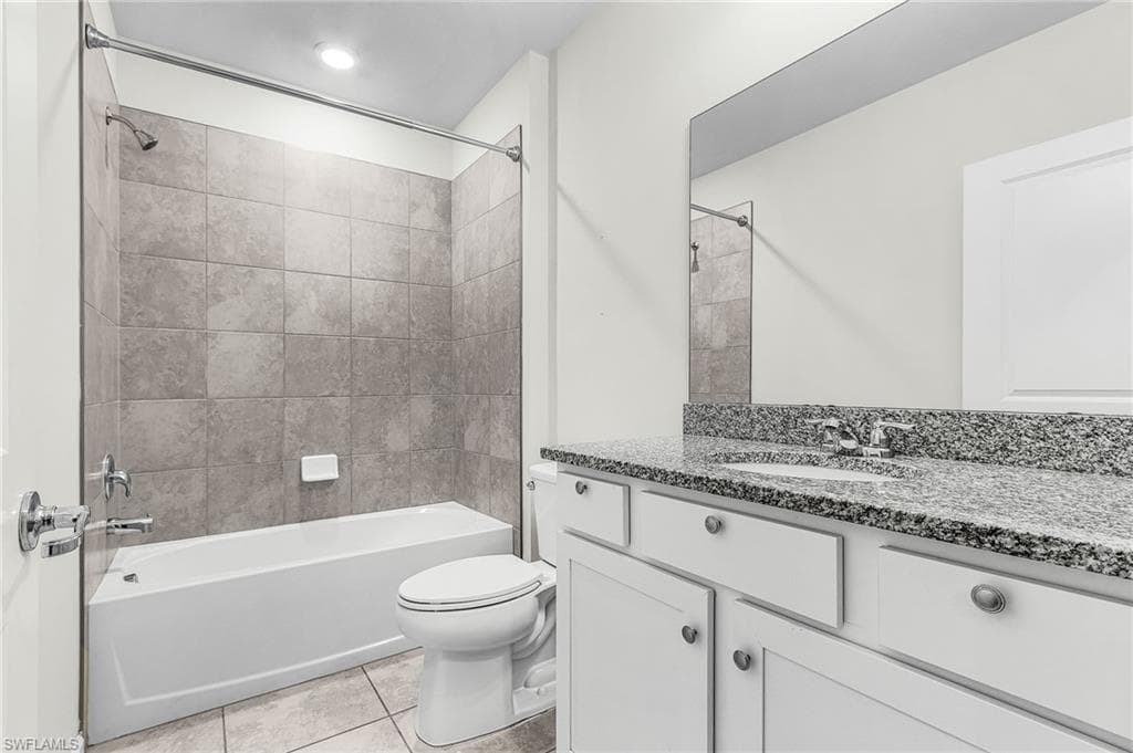 Full bathroom with large granite counter top vanity, tub/shower combination, and light tile patterned floors