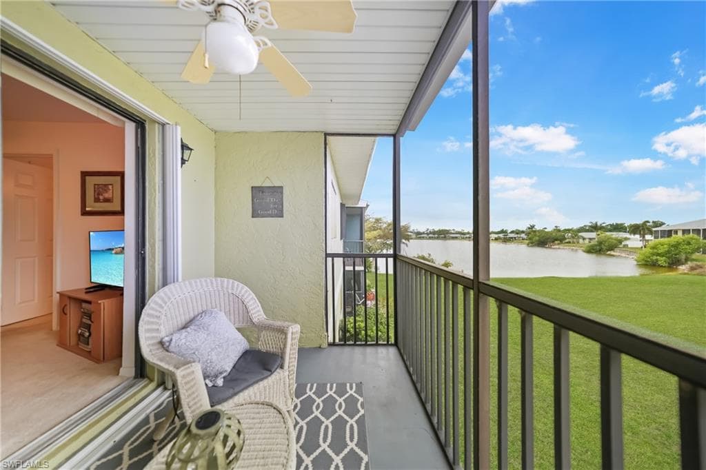 Sunroom with a water view, a balcony, and a ceiling fan