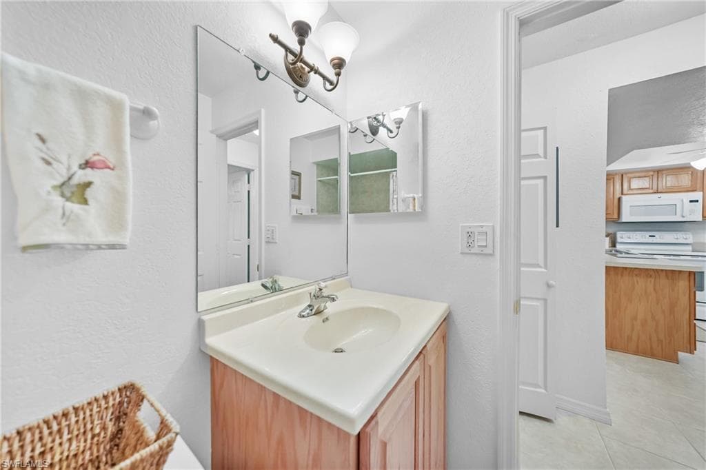 Bathroom with a textured wall, vanity, and light tile patterned floors