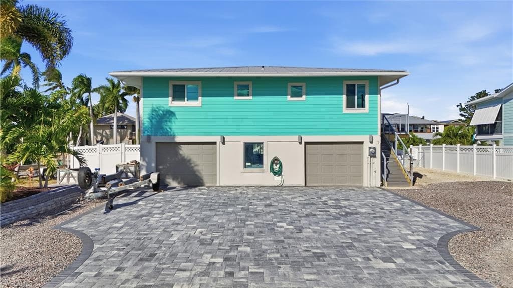 Rear view of house with decorative driveway, an attached garage, and a metal roof - Virtually Edited Image