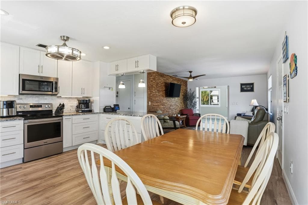 Dining area featuring ceiling fan, light wood finished floors, and recessed lighting - Virtually Edited Image