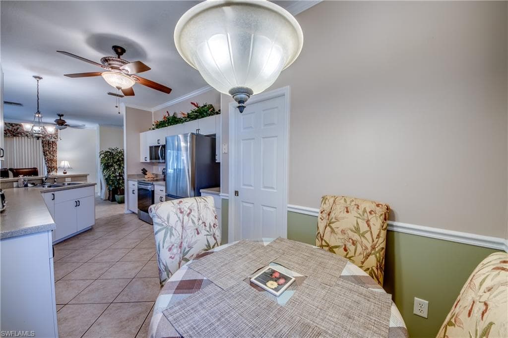 Dining space featuring light tile patterned flooring, crown molding, and ceiling fan