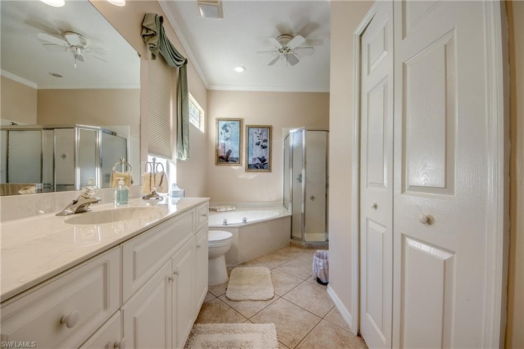 Bathroom with a closet, a shower stall, vanity, a garden tub, and crown molding