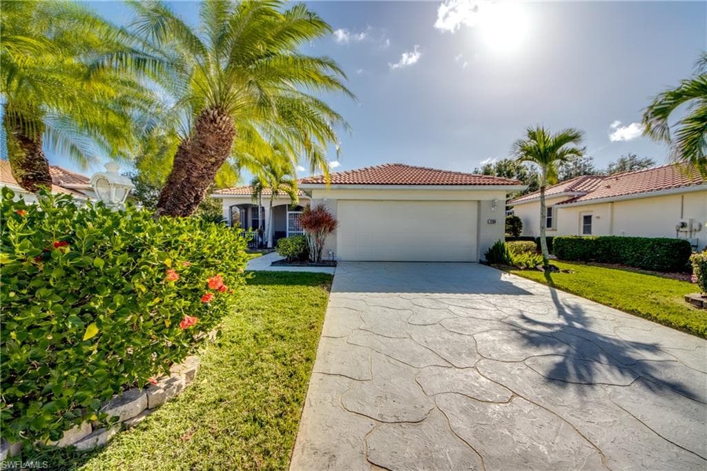 View of front of home featuring driveway, stucco siding, a front yard, and a tiled roof