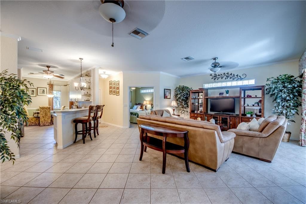 Living area featuring ceiling fan, crown molding, and light tile patterned floors