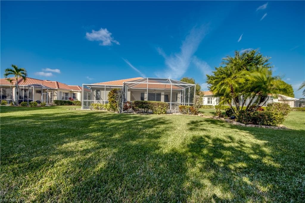 Rear view of property with a yard, a lanai, and a sunroom