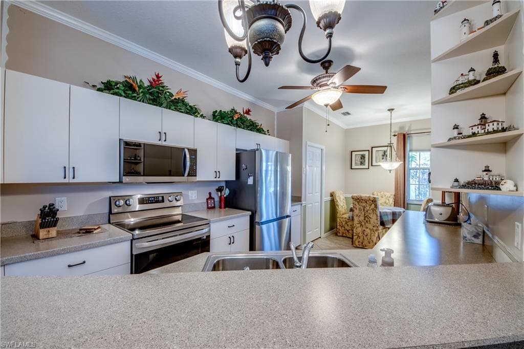 Kitchen with stainless steel appliances, open shelves, ornamental molding, white cabinetry, and a chandelier