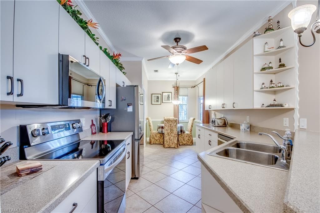 Kitchen featuring appliances with stainless steel finishes, crown molding, open shelves, light countertops, and hanging light fixtures