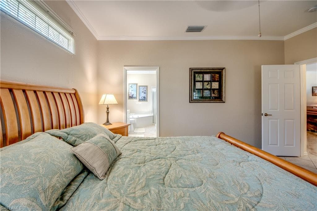 Bedroom featuring ornamental molding, ensuite bath, and a ceiling fan