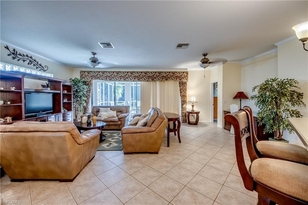 Living area with light tile patterned floors, crown molding, and a ceiling fan