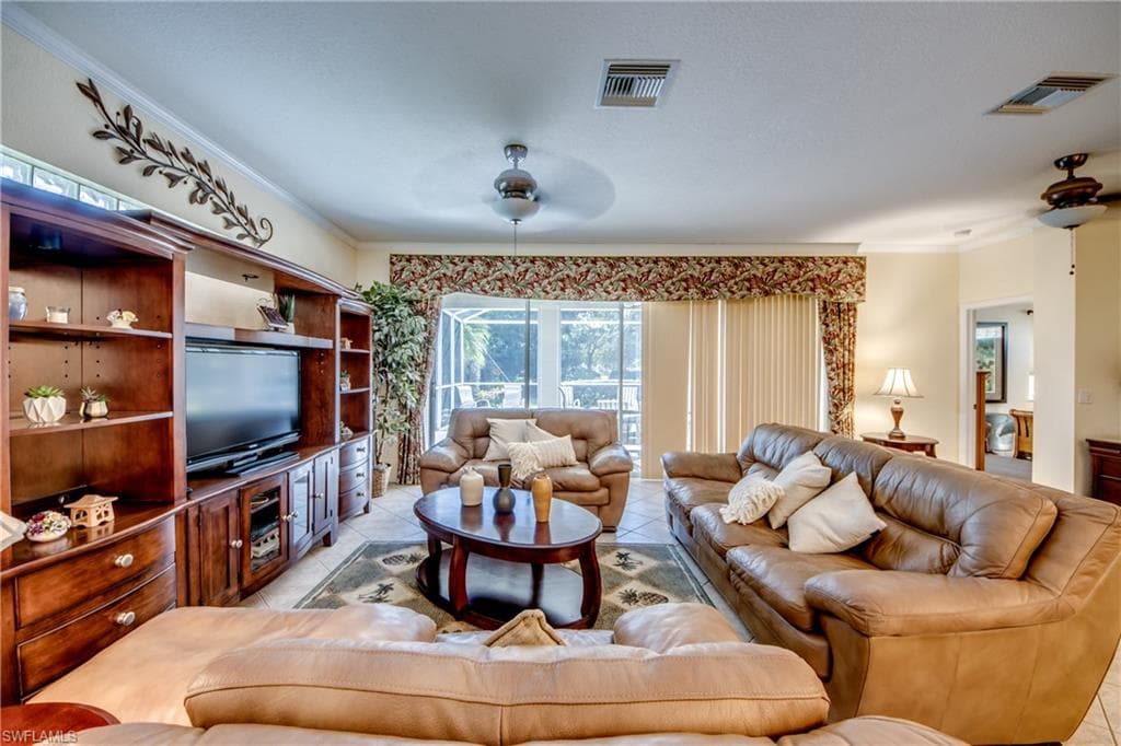 Living area featuring crown molding, light tile patterned flooring, and ceiling fan