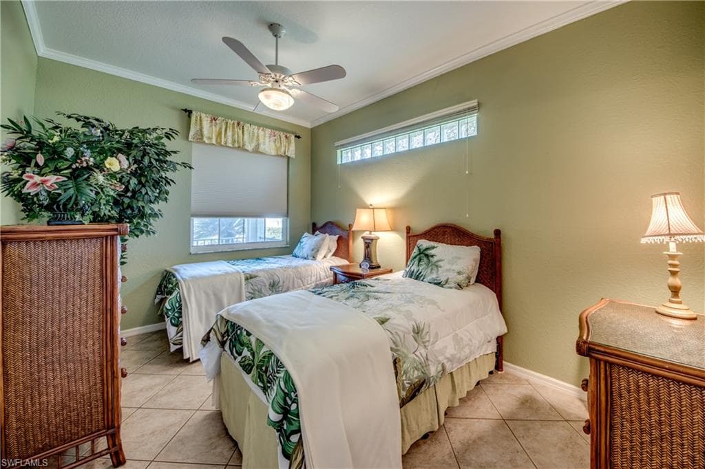 Tiled bedroom featuring ornamental molding and a ceiling fan