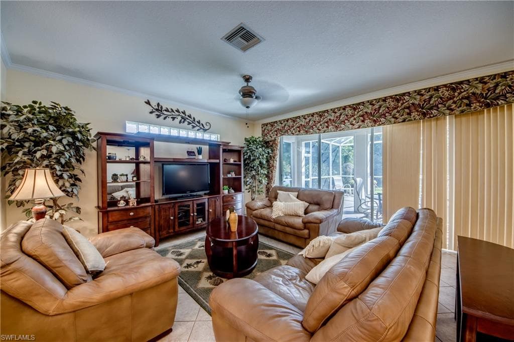 Living area with ornamental molding, ceiling fan, and light tile patterned floors