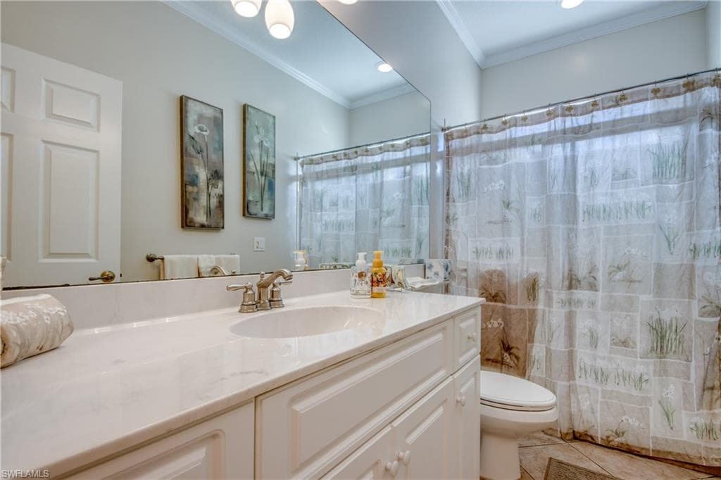 Full bath with a shower with shower curtain, crown molding, vanity, and light tile patterned floors
