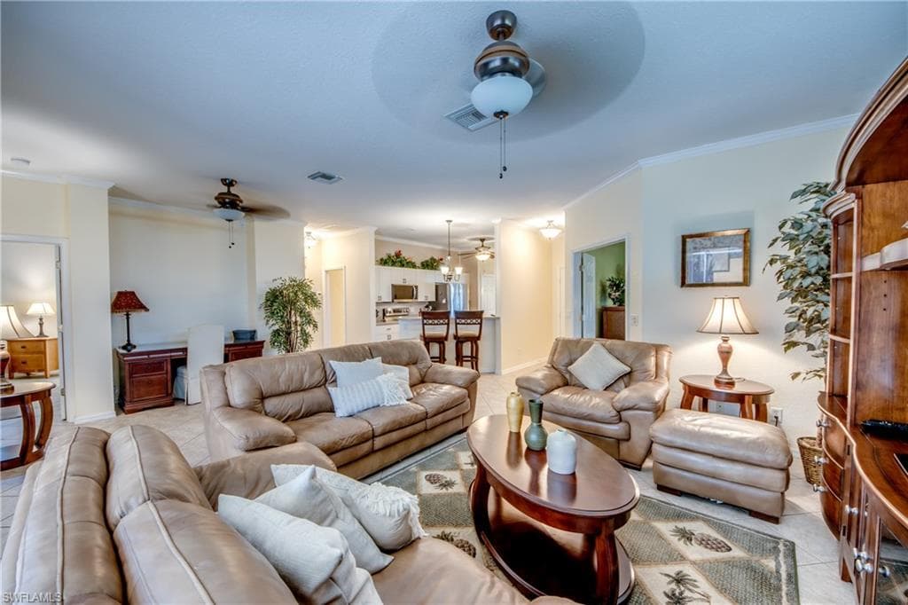 Tiled living area with ornamental molding and ceiling fan