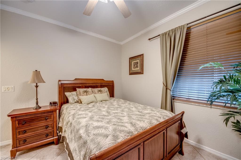 Bedroom featuring crown molding, light tile patterned floors, and a ceiling fan