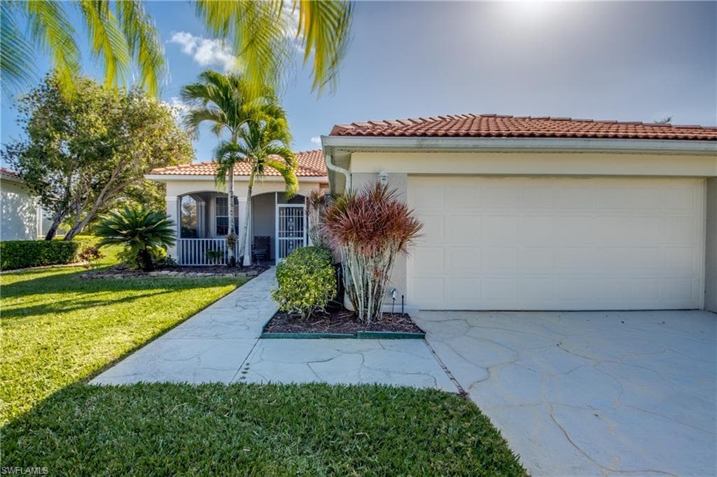 Mediterranean / spanish-style house featuring concrete driveway, stucco siding, a front yard, a tiled roof, and a garage