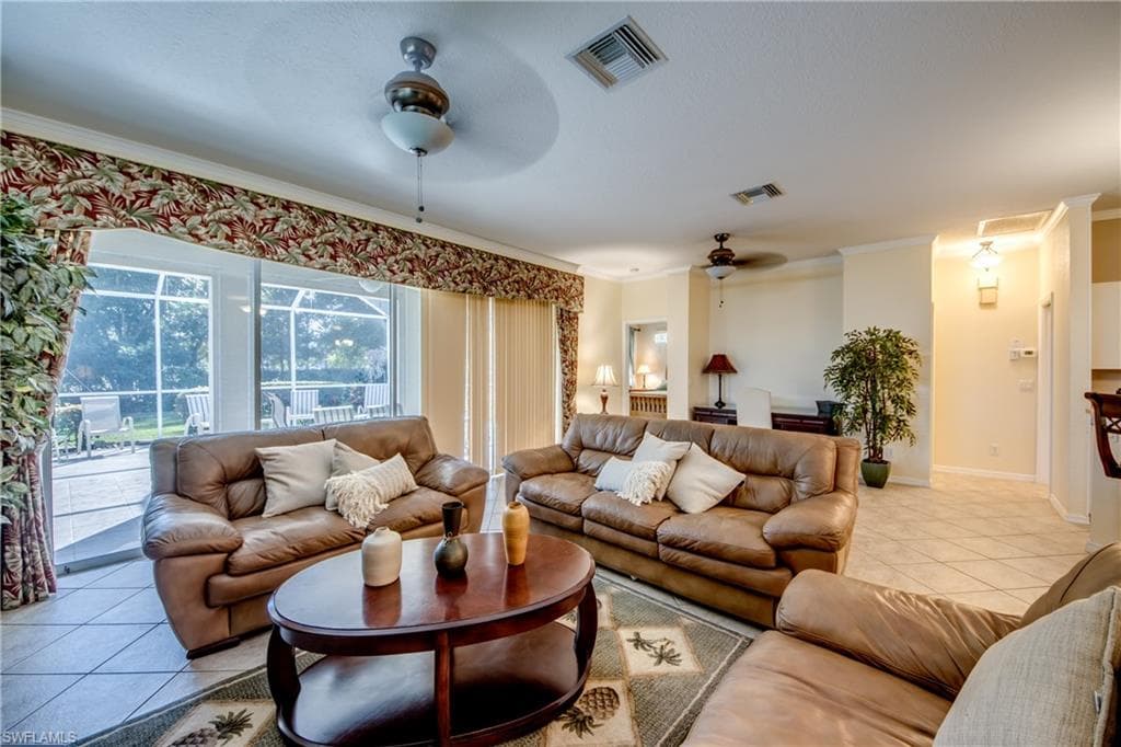 Living room featuring light tile patterned flooring, crown molding, and ceiling fan