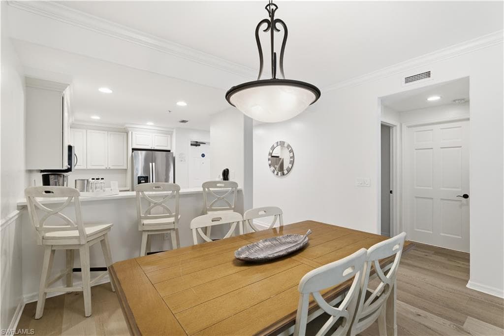 Dining room with recessed lighting, crown molding, and light wood-type flooring