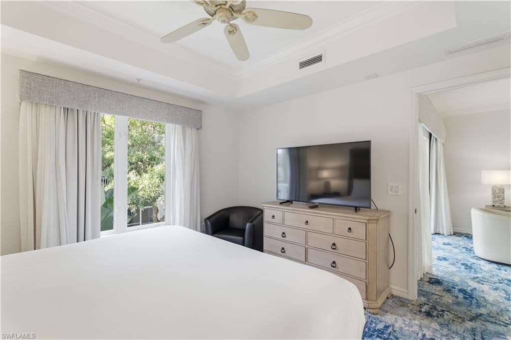 Bedroom featuring ornamental molding, a raised ceiling, and ceiling fan