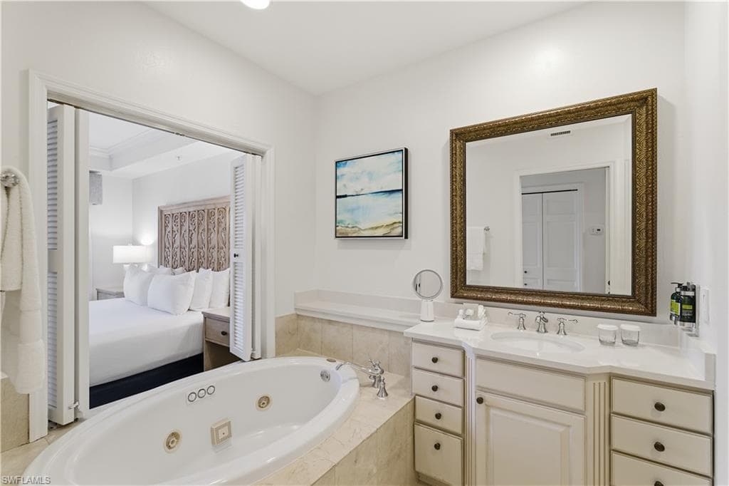 Full bathroom featuring a whirlpool tub, vanity, connected bathroom, and a closet