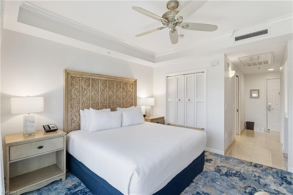 Bedroom featuring a raised ceiling, a closet, a ceiling fan, ornamental molding, and attic access