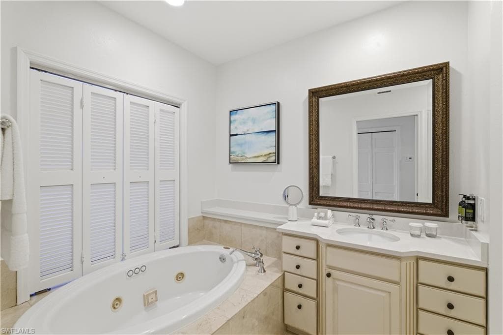 Full bath with a tub with jets, vanity, and a closet