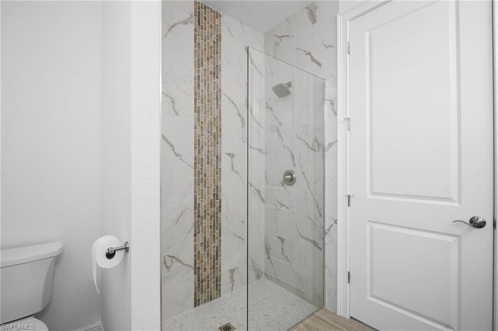 Full bathroom featuring a marble finish shower and toilet