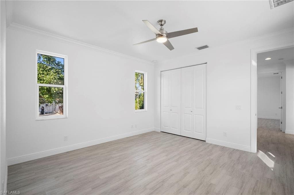 Unfurnished bedroom with light wood-type flooring, ornamental molding, ceiling fan, and a closet