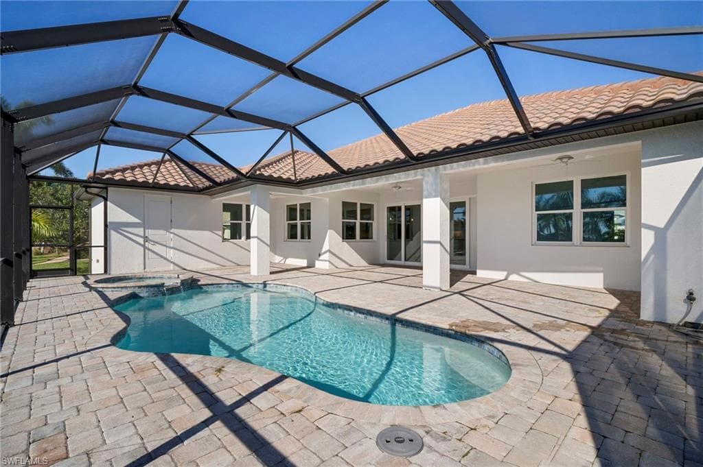 View of swimming pool featuring a sunroom, a pool with connected hot tub, a lanai, and a patio area