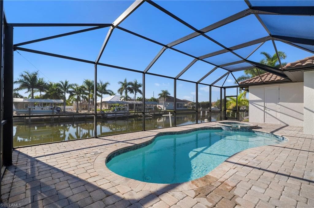 View of swimming pool with a lanai, a pool with connected hot tub, a sunroom, a water view, and a patio