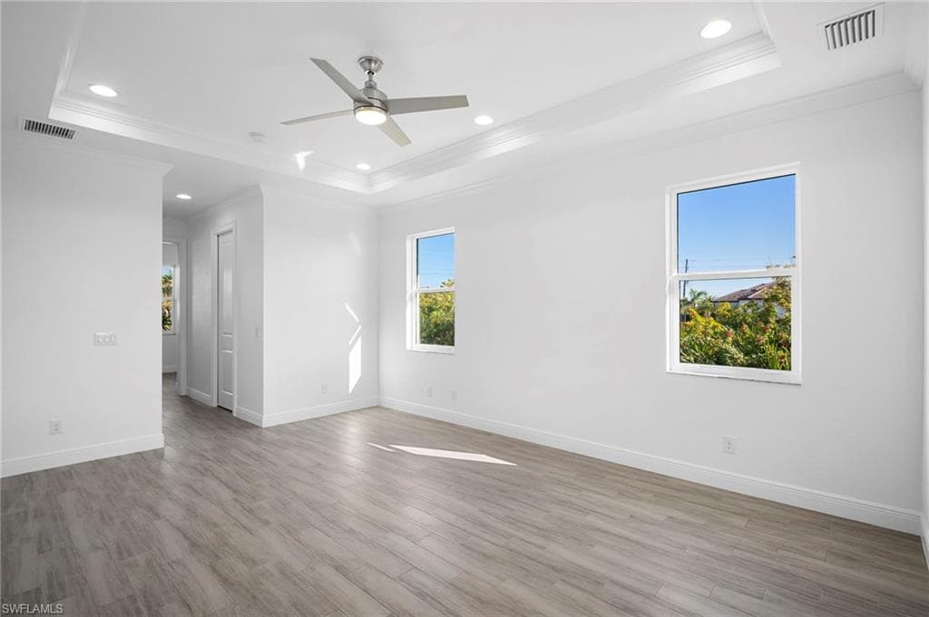 Spare room featuring recessed lighting, light wood-style floors, a raised ceiling, a ceiling fan, and crown molding
