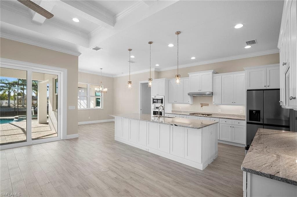 Kitchen with white cabinetry, crown molding, light stone counters, decorative light fixtures, and recessed lighting