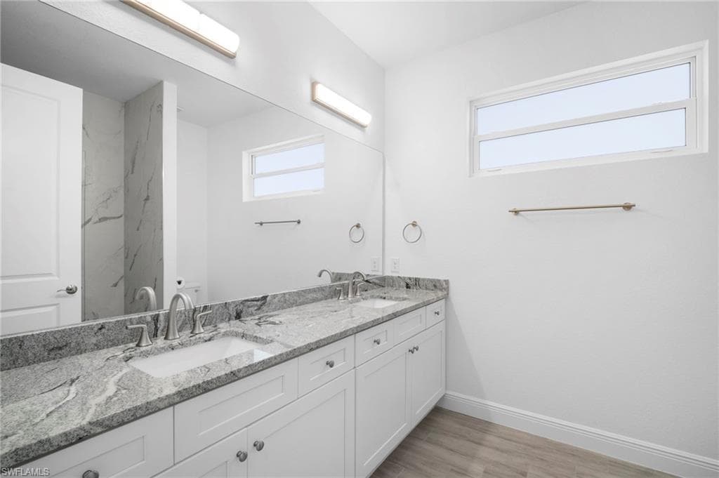 Bathroom featuring double vanity and light wood-style flooring