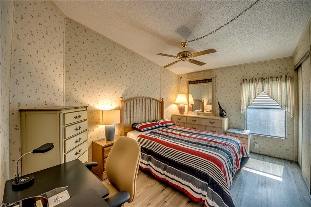 Bedroom featuring a textured ceiling, light wood finished floors, and ceiling fan