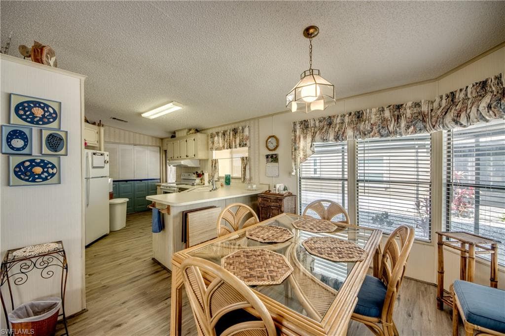 Dining space with a textured ceiling and light wood-style flooring