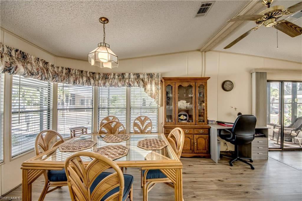 Dining room with light wood-style floors, plenty of natural light, a textured ceiling, and a ceiling fan
