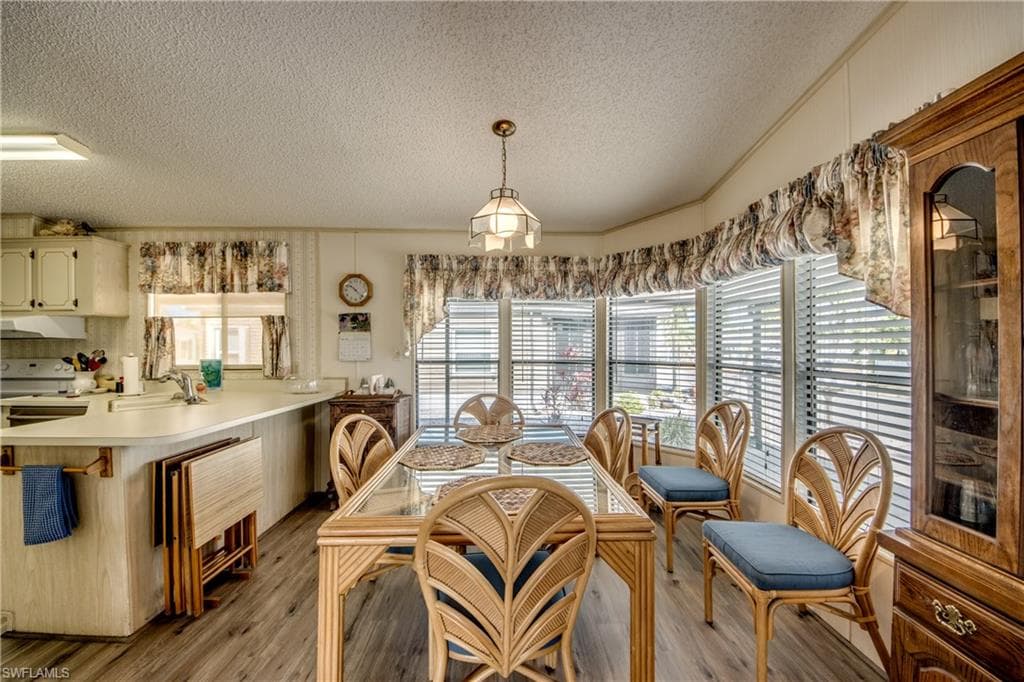 Dining room with a textured ceiling, light wood-style flooring, and vaulted ceiling