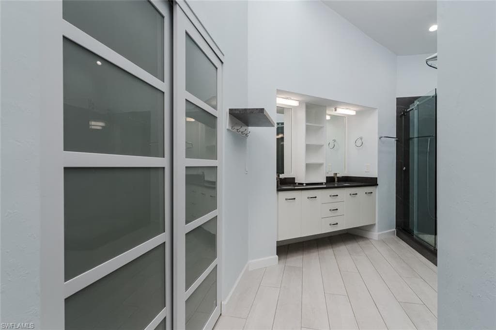 Full bathroom with a stall shower, double vanity, and light wood-type flooring