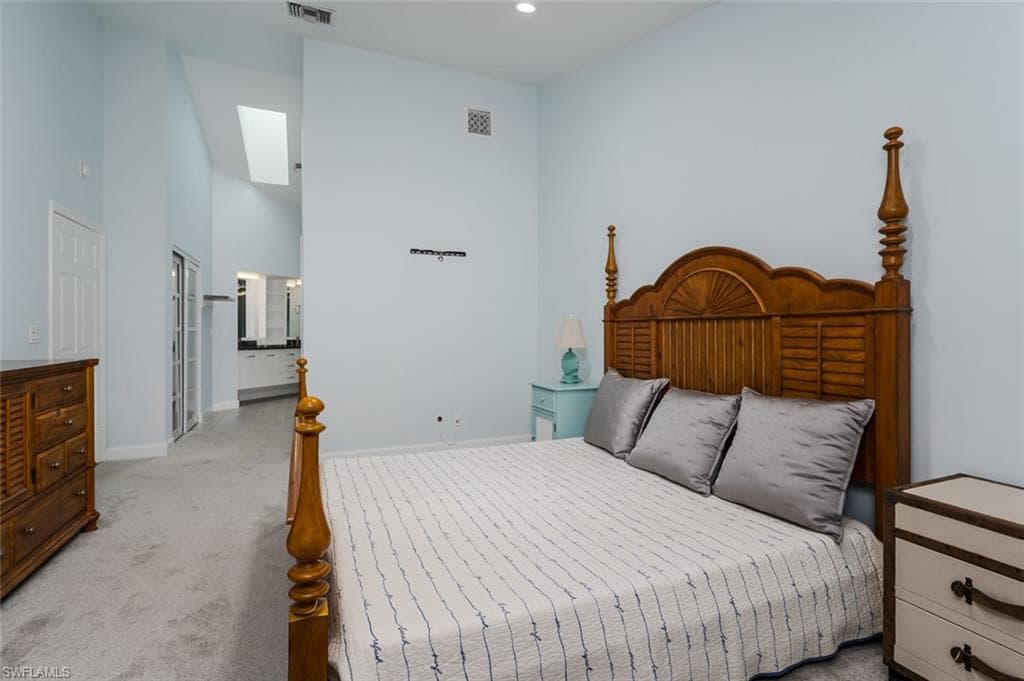 Bedroom with a high ceiling, carpet, ensuite bath, and recessed lighting