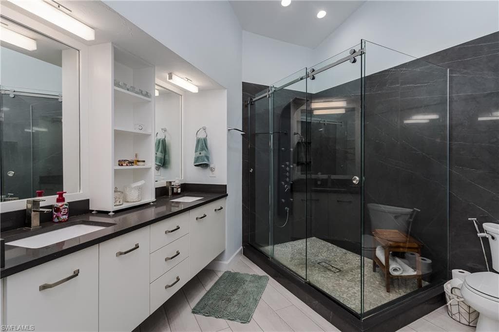 Full bath featuring double vanity, a shower stall, and light tile patterned floors
