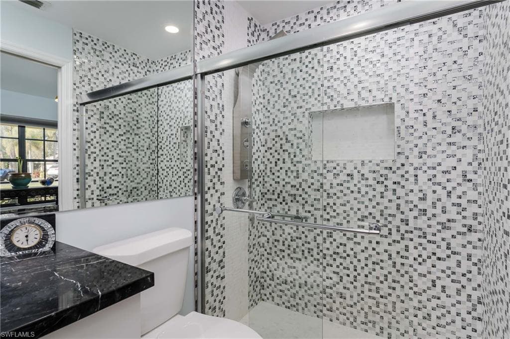 Full bath featuring a shower stall and toilet