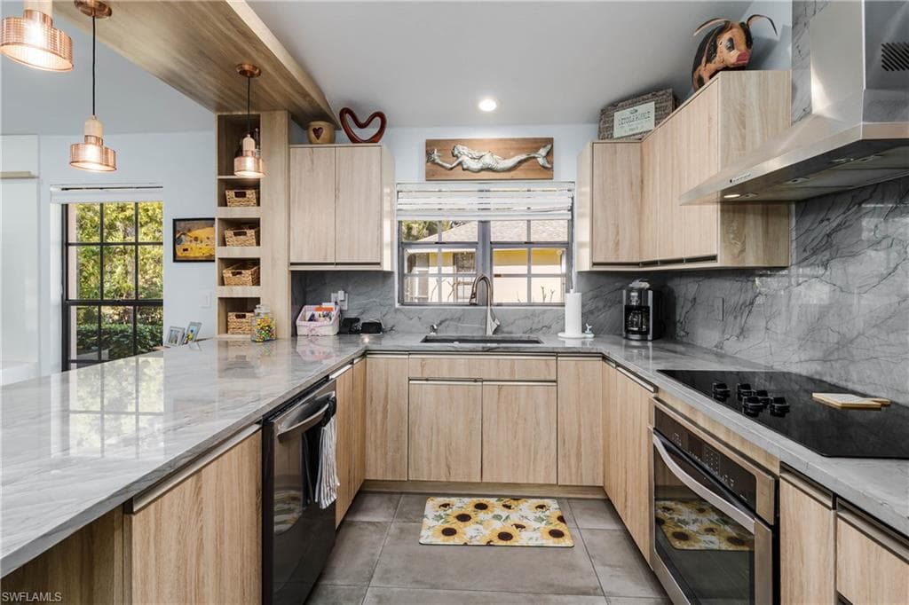 Kitchen featuring light brown cabinets, wall chimney range hood, light stone counters, oven, and recessed lighting