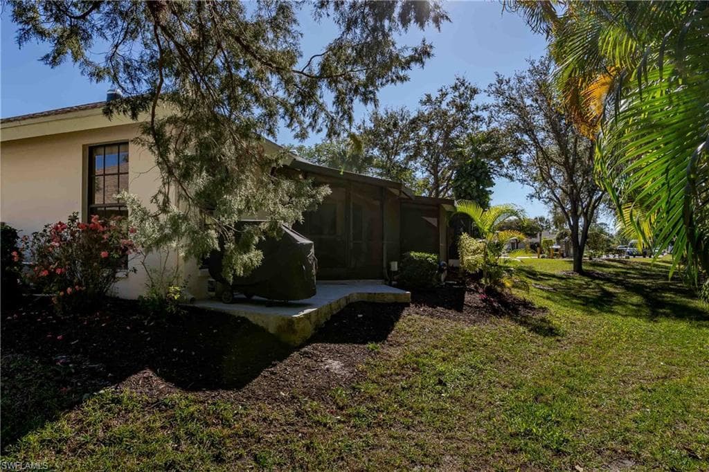 View of property exterior featuring a sunroom, stucco siding, and a lawn